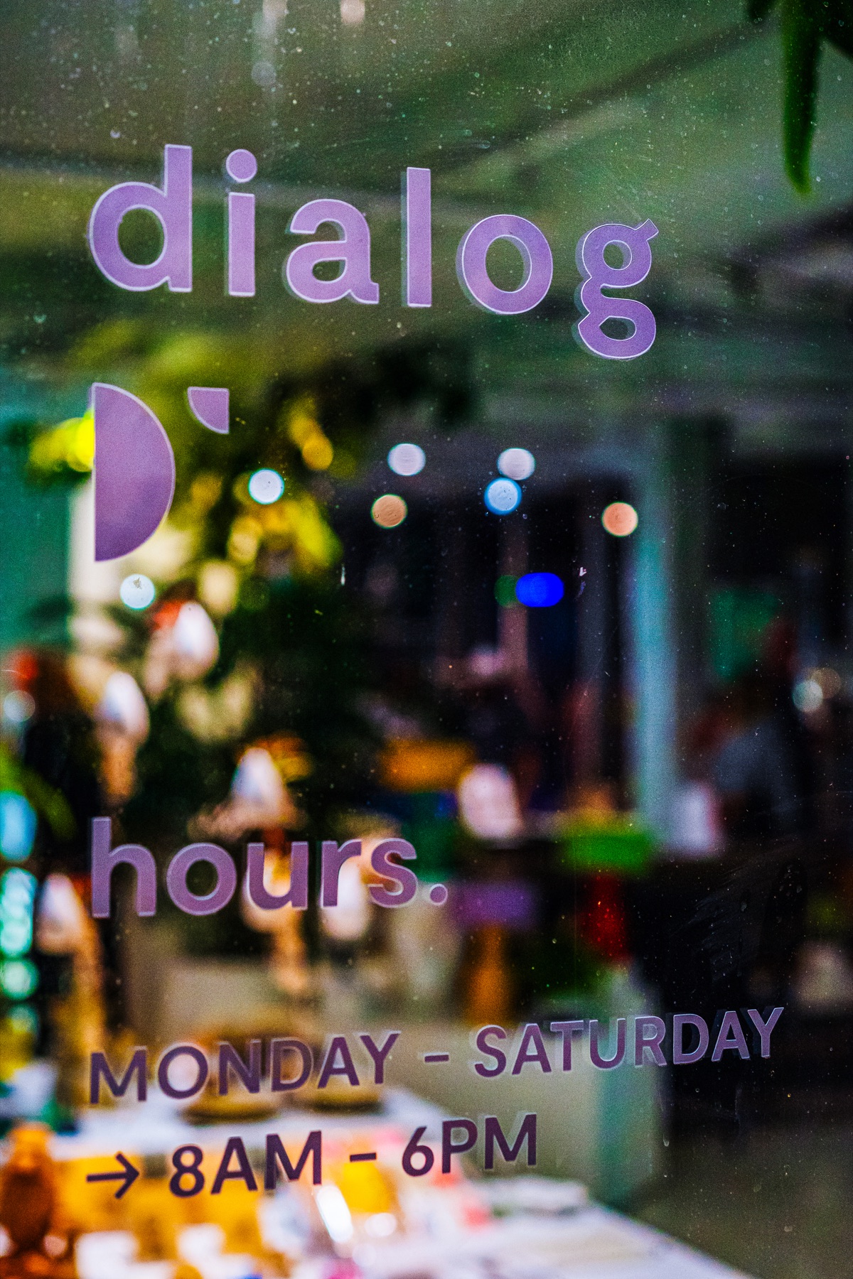 The Dialog storefront lettering glows against reflections of the opening-night crowd.