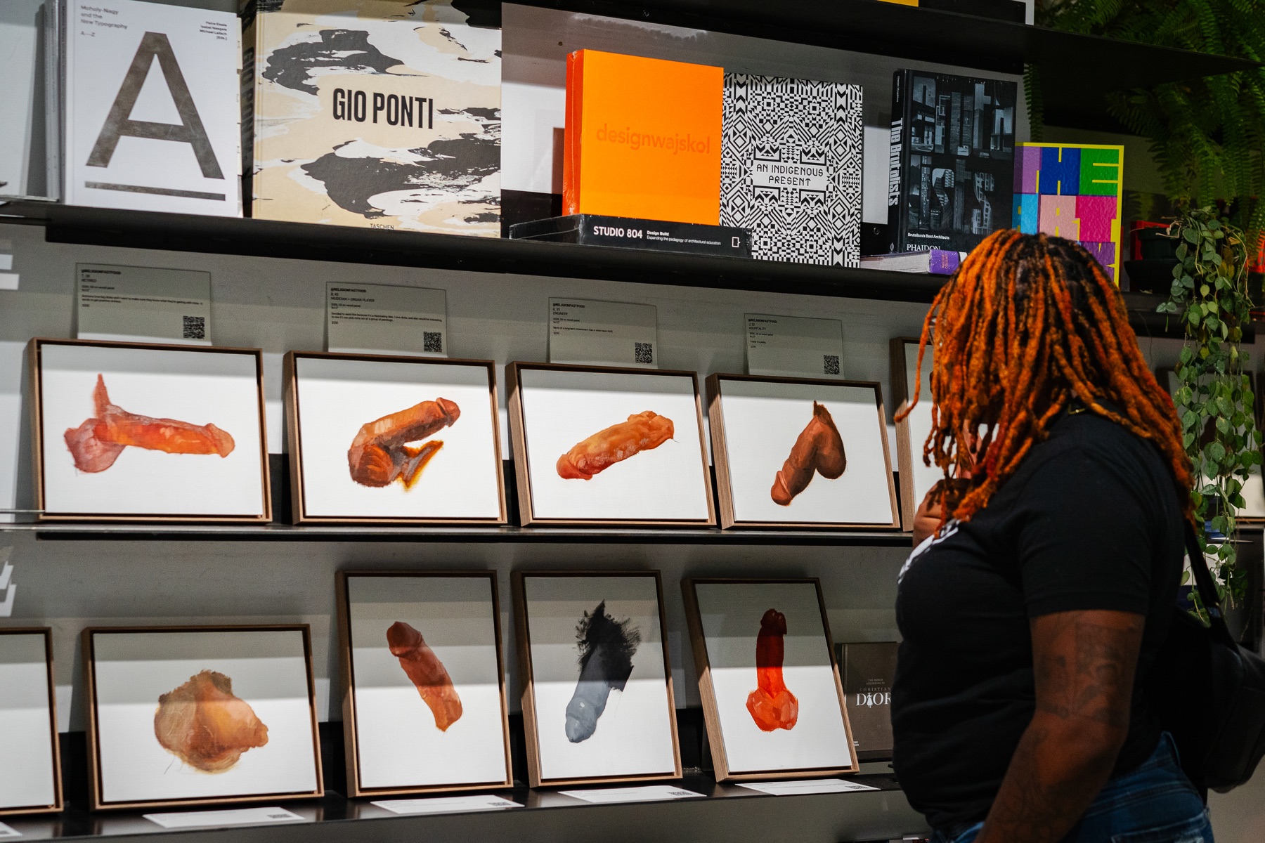 A visitor looks at a shelf lined with Christian McDonald’s framed paintings at Dialog.