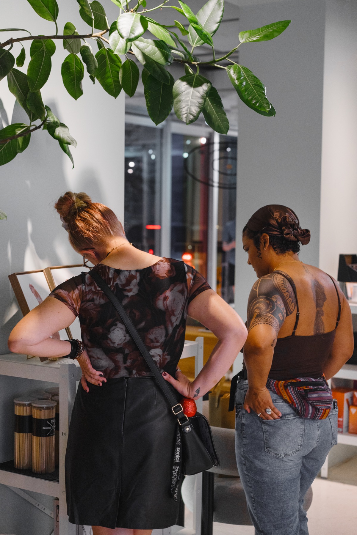 Two visitors lean in to read the personal messages paired with the paintings.
