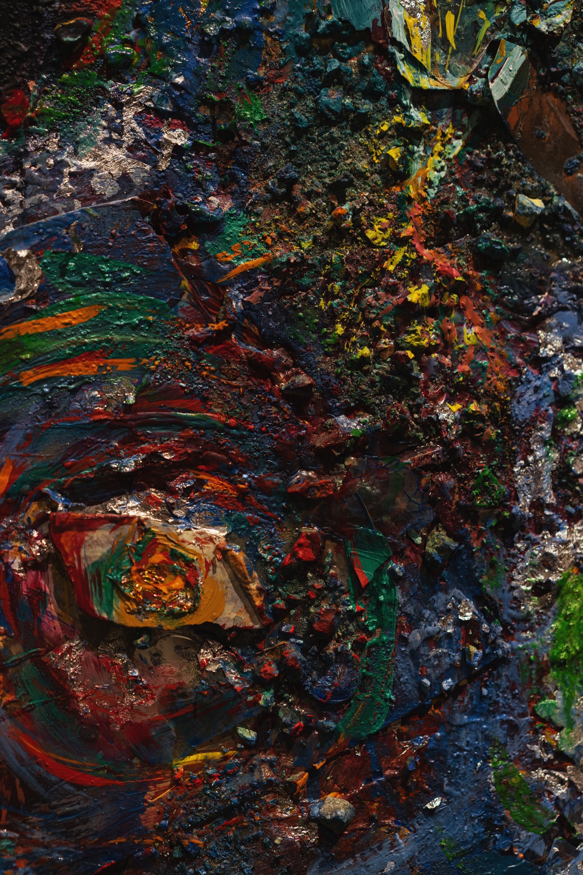 Close detail of dense painted material in green, blue, red, yellow, and silver.