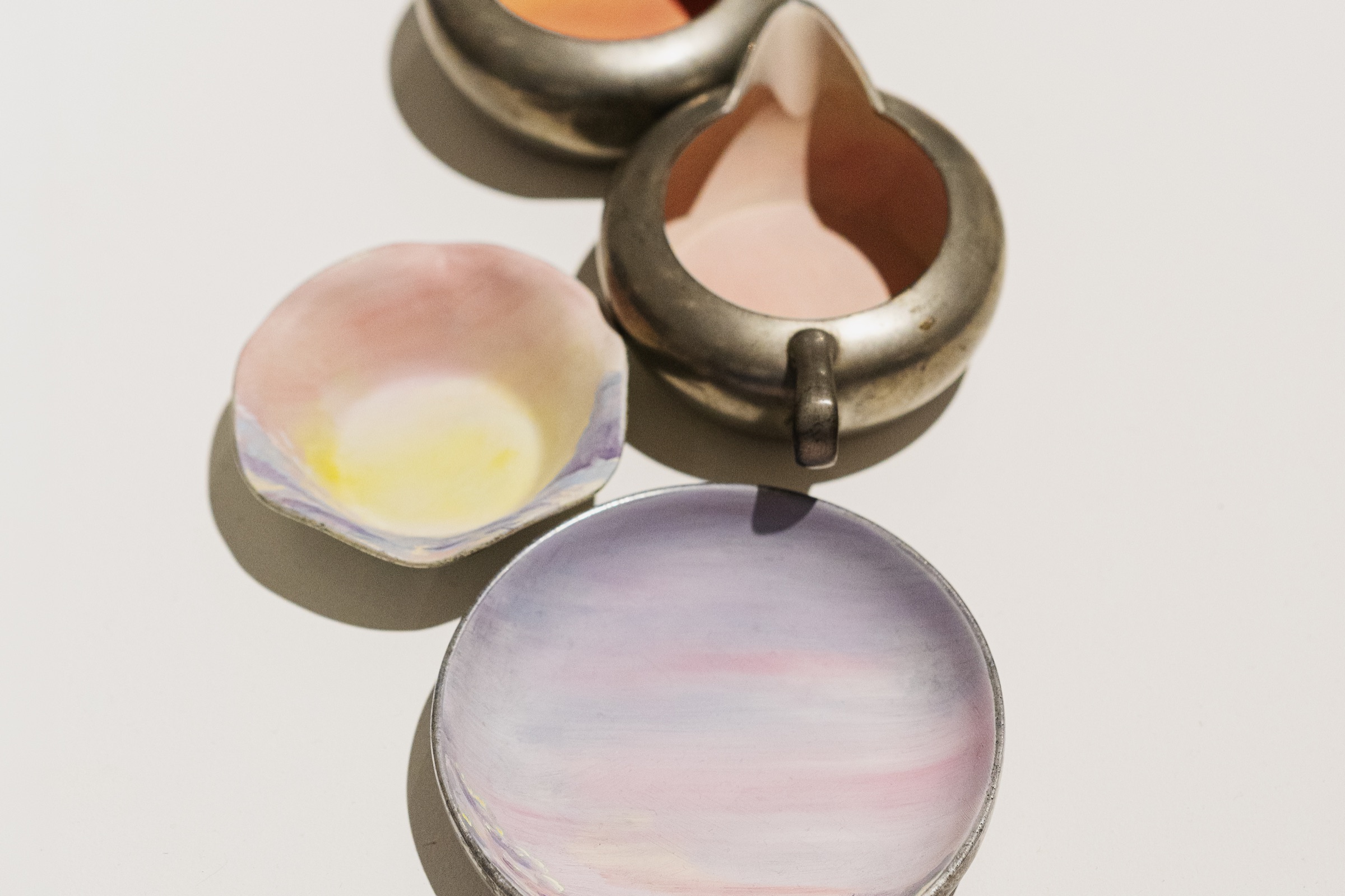 Softly painted pastel bowls and vintage metal vessels are seen from above.