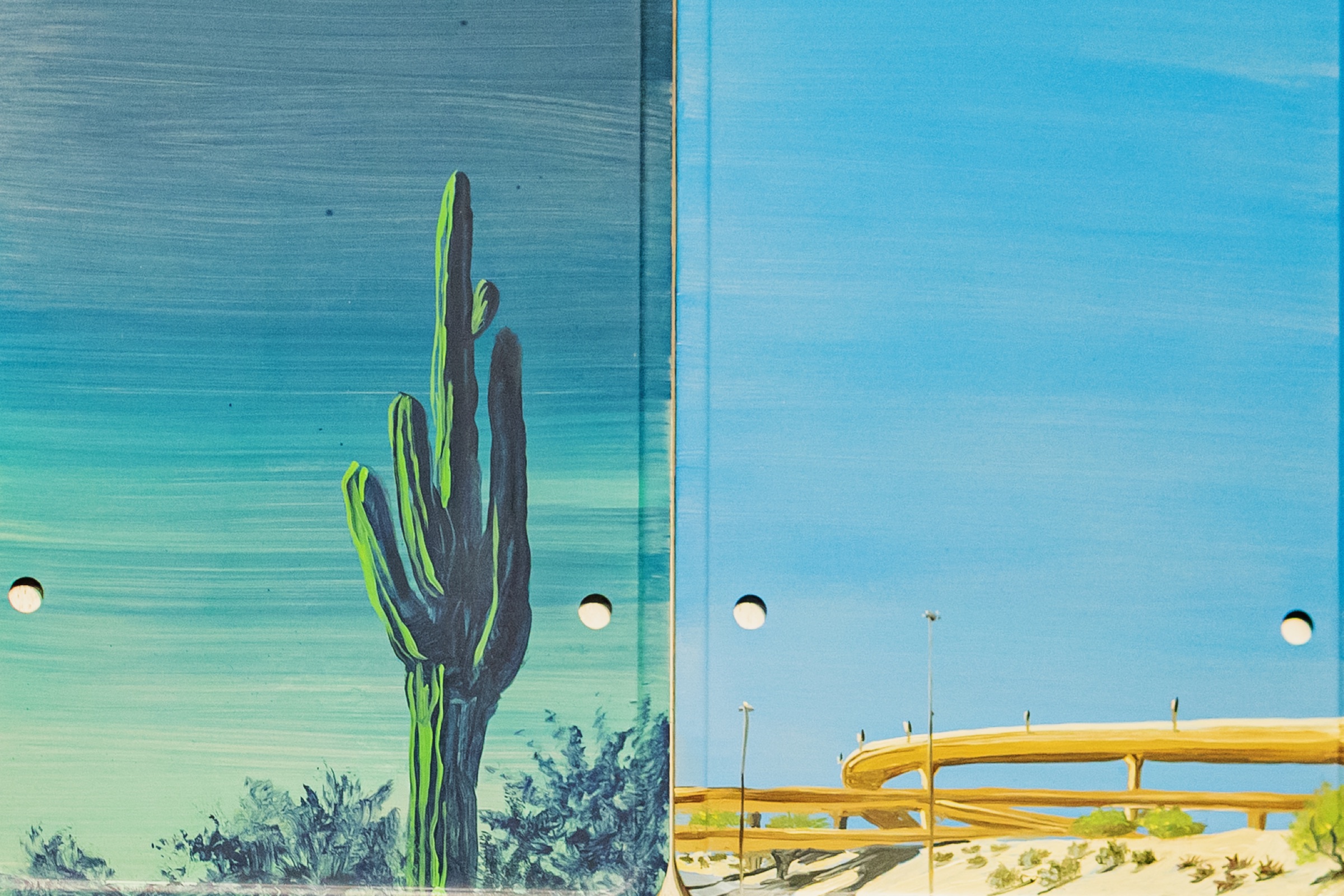 Painted found objects pair a dark saguaro with a looping desert highway.