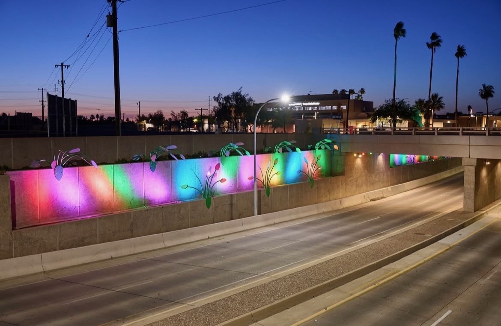 Sun Garden glowing in pink, green, blue, and yellow along the Mill Avenue underpass in Tempe at night.