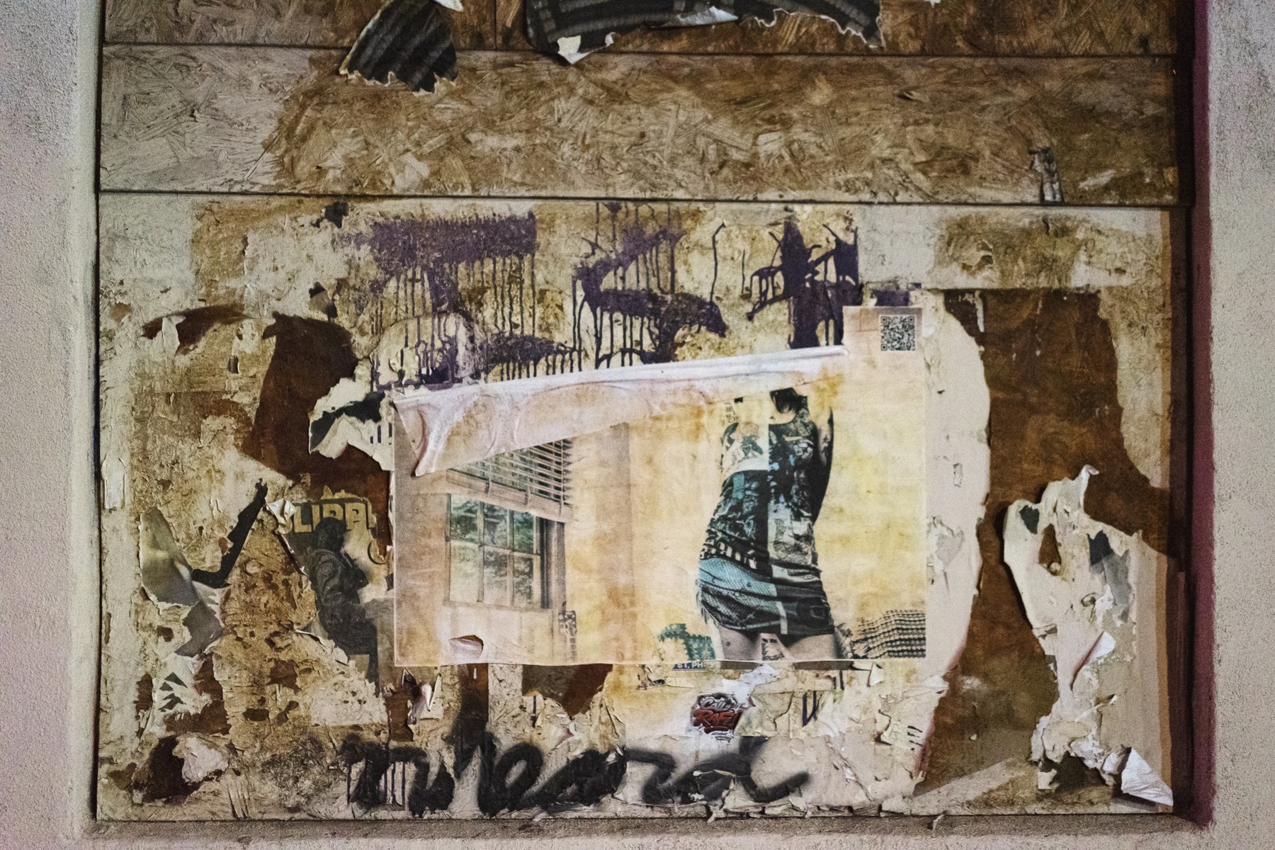 A torn wheat-pasted artwork of a figure on a heavily layered Phoenix wall.