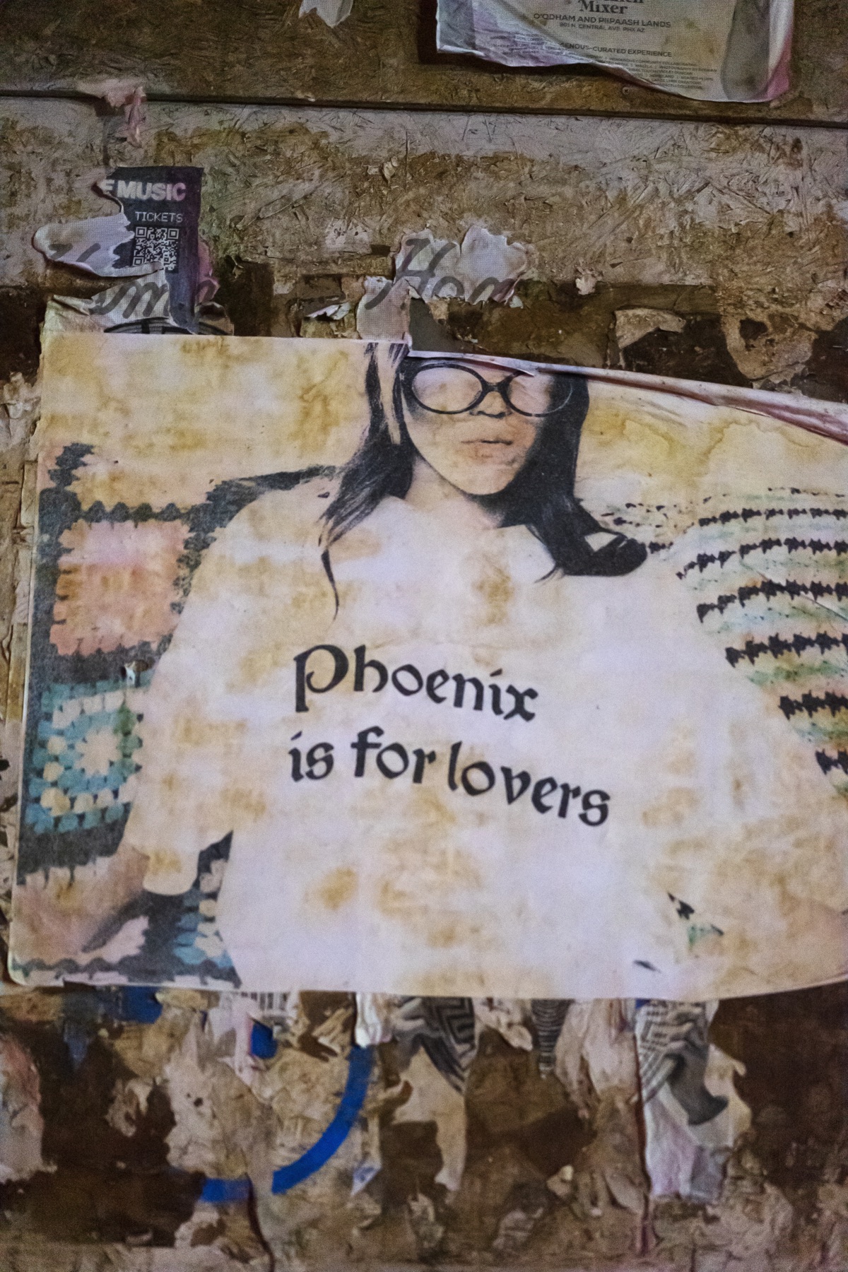 A close-up wheat-pasted portrait reading Phoenix is for lovers.